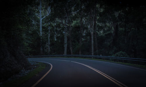 Empty road amidst trees in forest