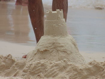 Low section of woman on sand at beach