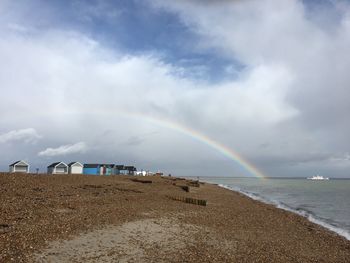 Rainbow over beach against sky