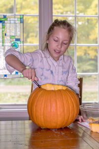 A cute little girl works on carving a jack o lantern in time for halloween