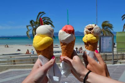 Midsection of women holding ice cream on beach