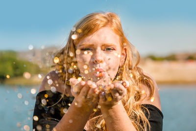 Portrait of smiling teenage girl blowing confetti