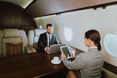 Businessman and secretary sitting in corporate jet