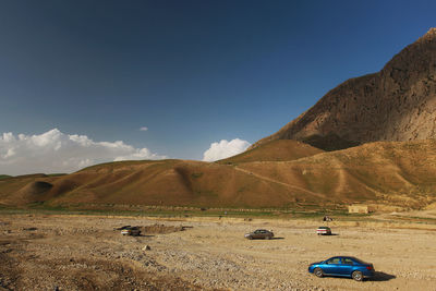 Scenic view of land and mountains against blue sky