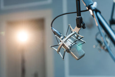 A professional condenser microphone mounted on a tripod set up in a concert hall with spot lighting. 