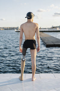 Amputee male looking at sea while standing on promenade during sunny day