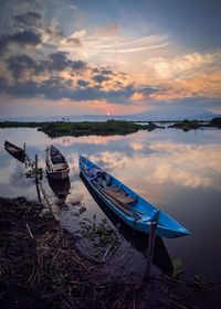 Boat moored on beach against sky during sunset