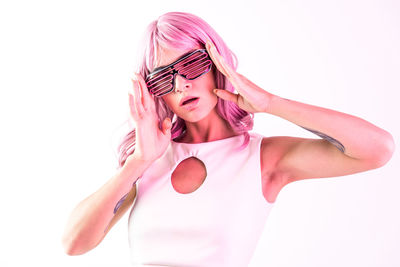 Portrait of young woman wearing sunglasses against white background