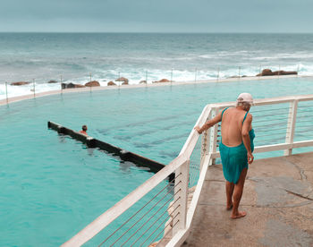 Rear view of men at beach against sky