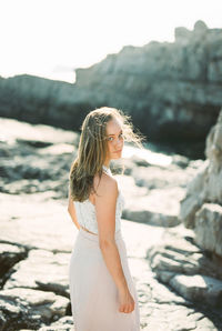 Side view of young woman standing on rock