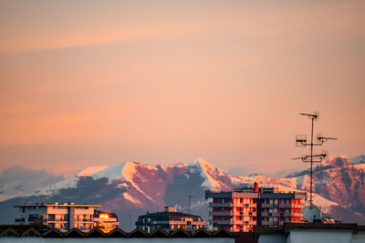 Buildings and mountains against sky at sunset