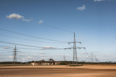 Electricity pylon on field against sky