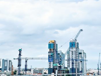 Cranes at construction site against sky in city