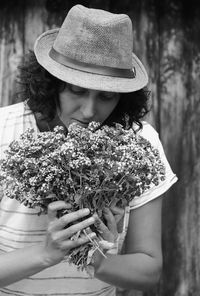 Woman wearing hat smelling flower bouquet