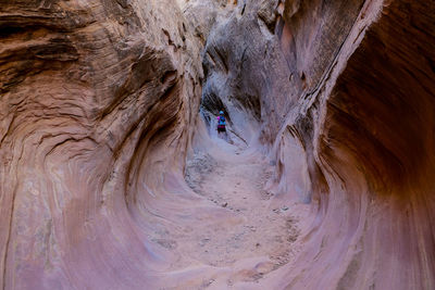 Rear view of mid adult woman standing amidst rock formation in cave