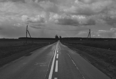 Empty road on field against cloudy sky