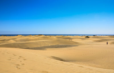 Scenic view of desert against clear blue sky