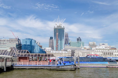 Modern buildings by river against sky in city