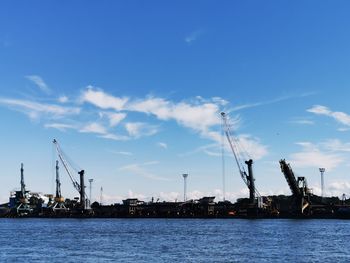 Cranes at commercial dock against sky