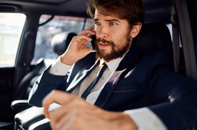 Young man using mobile phone in car