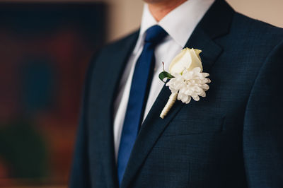 Midsection of groom with flower on suit