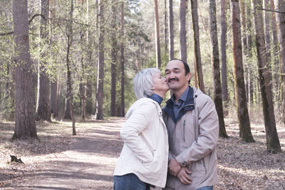 Happy friends standing on land in forest