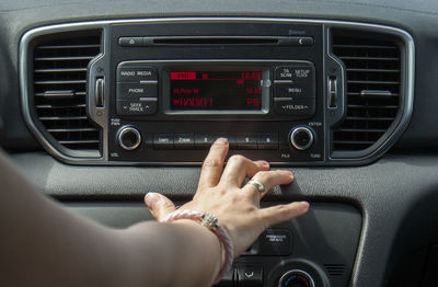 Cropped hand of woman operating radio in car