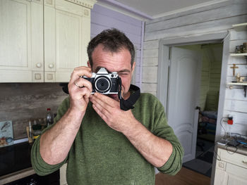Man photographing from camera in kitchen at home