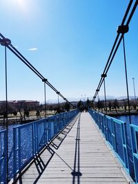 Footbridge over river against clear blue sky