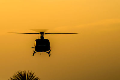 Low angle view of silhouette helicopter against sky during sunset