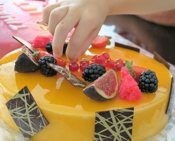 Cropped image of hand picking fruit on cake