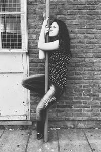 Young woman standing against brick wall