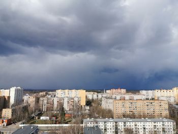 Buildings in city against storm clouds