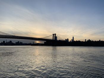 View of suspension bridge over river at sunset