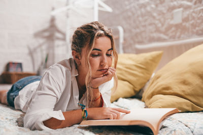 Portrait of young woman sitting on bed at home