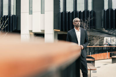 Confident black businessman leaning on railing