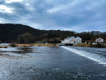 Houses by river and buildings against sky