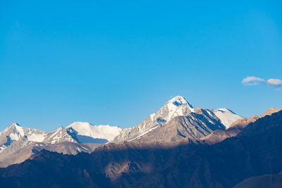 Scenic view of snowcapped mountains against clear blue sky