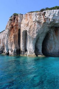 Rock formations in sea against clear blue sky