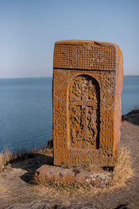 Scenic view of old gravestone against  lake against clear sky