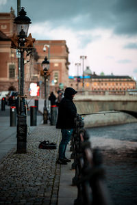 Rear view of man with bicycle on bridge in city