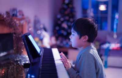 Side view of boy playing piano at home