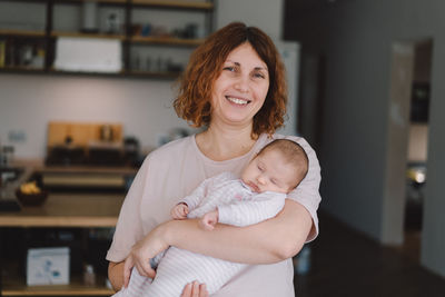 Portrait of happy mum holding infant child on hands.