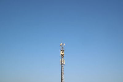 Low angle view of communications tower against clear blue sky