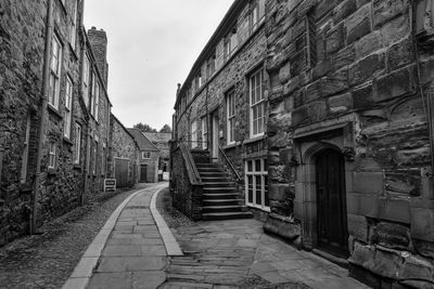 Footpath amidst old buildings against sky