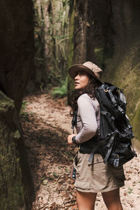 Young woman walking in a canyon with backpack looking back.