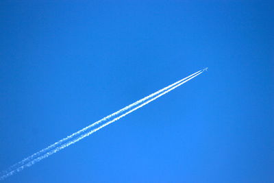 Low angle view of vapor trail against blue sky