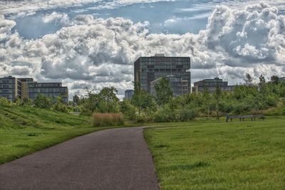 Road by buildings against sky in city