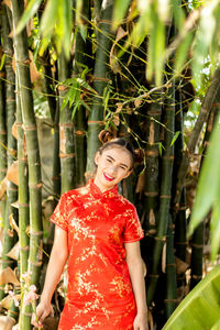 Young woman smiling while standing against plants