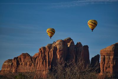 Low angle view of hot air balloons over rock formations against sky